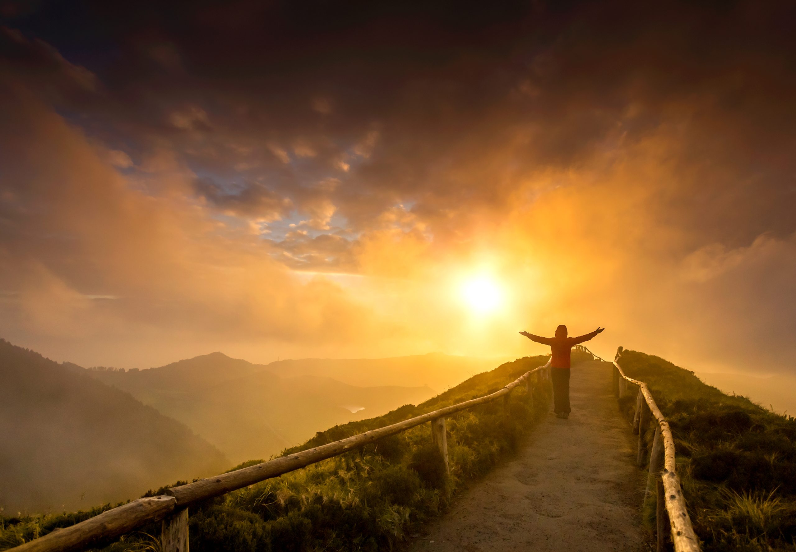 Woman Standing on a Beautiful Path with Arms Open at the Sunset